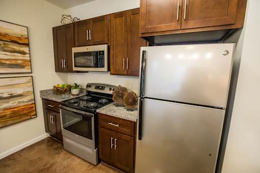 A kitchen with a stainless steel refrigerator, microwave, oven, and stove.