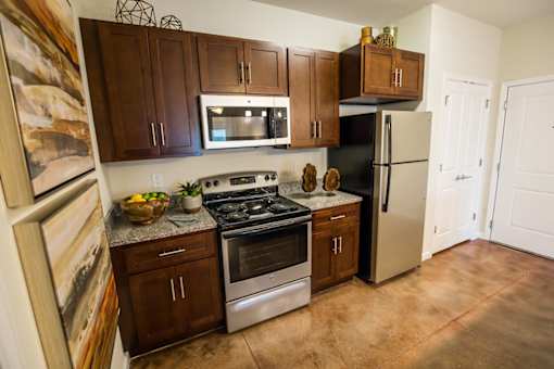 A kitchen with brown cabinets and a black refrigerator.