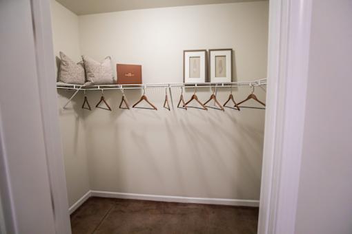 A white closet with a brown carpet and a brown hanger.