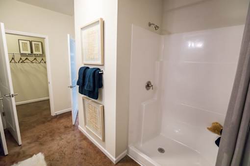 A bathroom with a white tub and a blue towel hanging on the door.