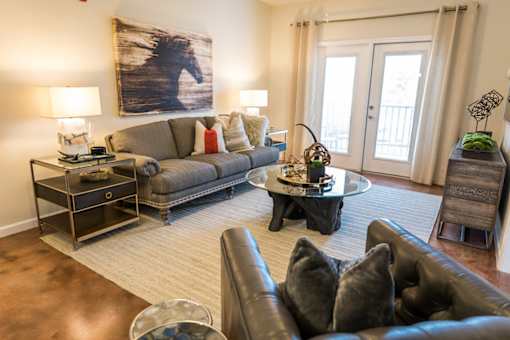 A living room with a brown leather couch and a painting of a horse on the wall.