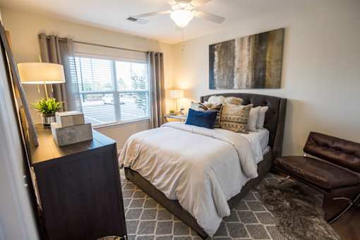 A bedroom with a large bed and a chair.