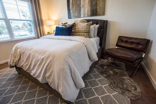 A bedroom with a large bed and a brown leather chair.