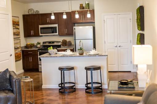 A kitchen with a white island and black stools.