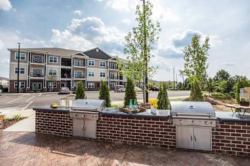 A brick wall with two grills on it in front of a building.