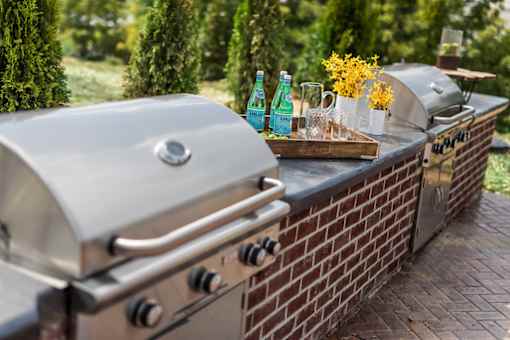 A silver grill with a tray of condiments and two bottles of soda on it.