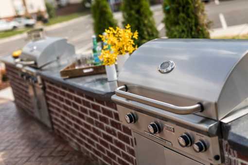 A silver grill with a vase of yellow flowers on top of it.