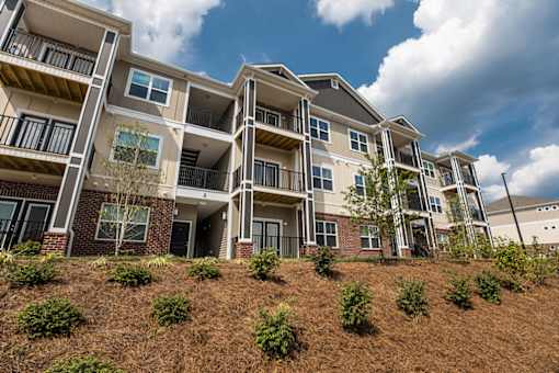 Apartment building with balconies and windows on a sunny day.
