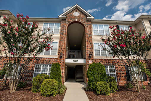 A red brick building with a large arched entrance and a walkway leading to it.