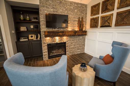 A living room with a stone fireplace and a television above it.