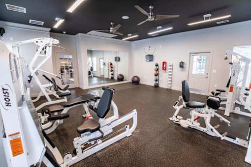 A gym with a variety of equipment including a weight bench and a leg press machine.