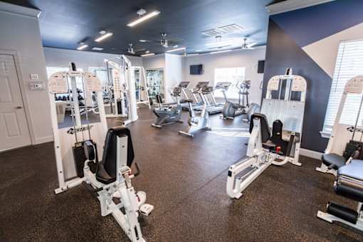 A gym with a variety of equipment including treadmills, weights, and exercise machines.