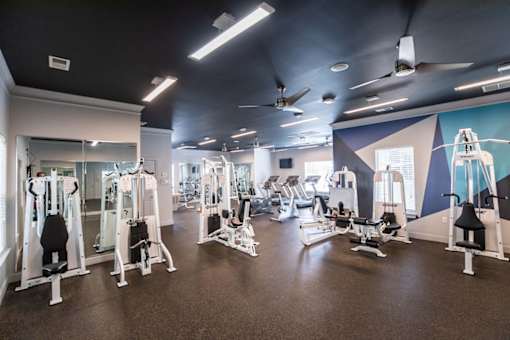 A gym with a variety of equipment including treadmills, weights, and exercise machines.