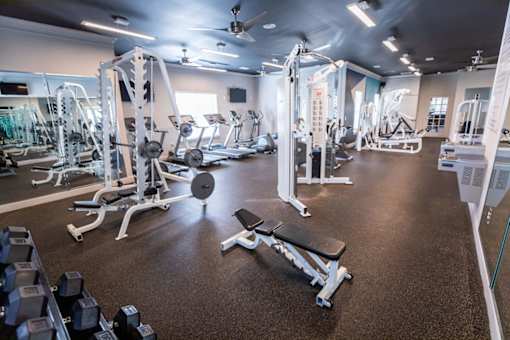 A gym with a variety of equipment including weights and weight machines.