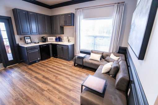 A kitchen with black cabinets and a brown couch.