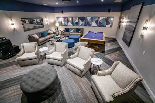 A room with a pool table and comfortable seating.