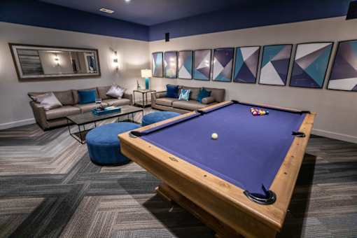 A pool table is in the middle of a room with a couch and a coffee table.