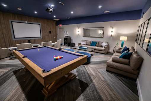 A pool table is surrounded by a couch and a TV in a room.