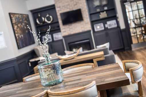 A glass vase with branches in it sits on a wooden table.