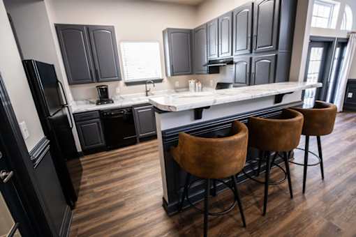 A kitchen with black cabinets and a white island.