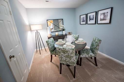 A dining room with a table set for two and a mirror on the wall.