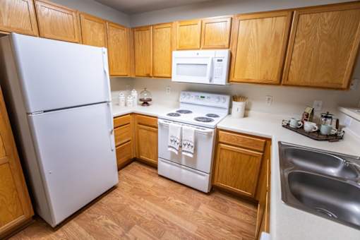 A kitchen with a white refrigerator, white oven, and wooden cabinets.