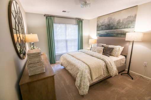 A bedroom with a bed, nightstand, and two lamps.
