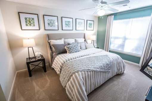 A bedroom with a bed, a nightstand, and a ceiling fan.