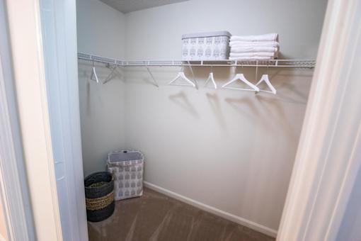 A white closet with a basket and towels on the shelf.