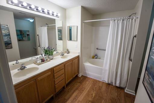 A bathroom with a white shower curtain and wooden cabinets.
