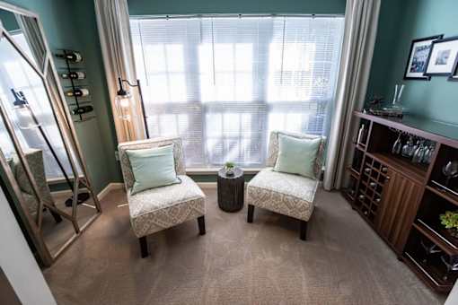 Two chairs with cushions are placed in front of a window.