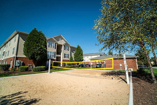 A sandy area in front of a building with a yellow fence.