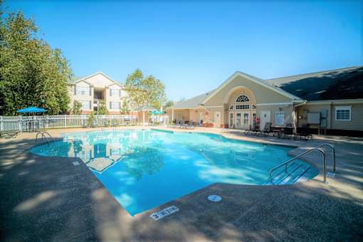 A large swimming pool in front of a building with a sunny sky.