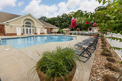 A pool area with a building and a potted plant.