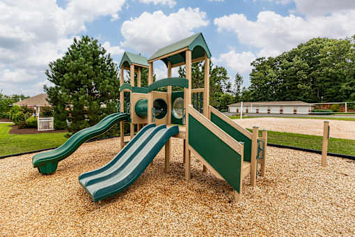 A playground with a green slide and a wooden structure.