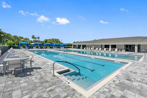 a swimming pool with tables and chairs around it