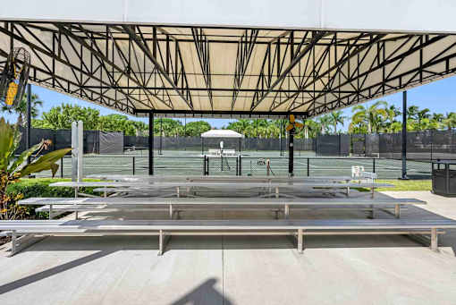 a covered pavilion over a tennis court with benches