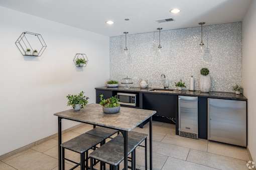 A kitchen with a table and chairs in front of a sink and a refrigerator.