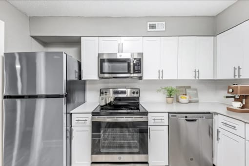 A modern kitchen with stainless steel appliances and white cabinets.