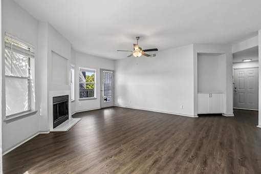 A spacious room with a fireplace and wood flooring.