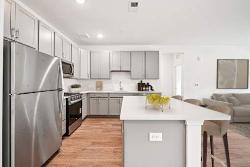 A modern kitchen with a stainless steel refrigerator and wooden flooring.