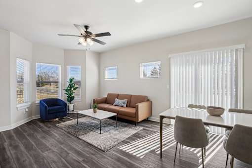 A living room with a blue chair, a brown couch, and a glass table.