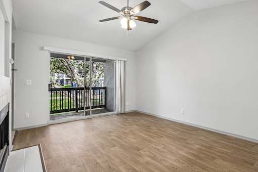 A room with a ceiling fan and sliding glass doors leading to a balcony.
