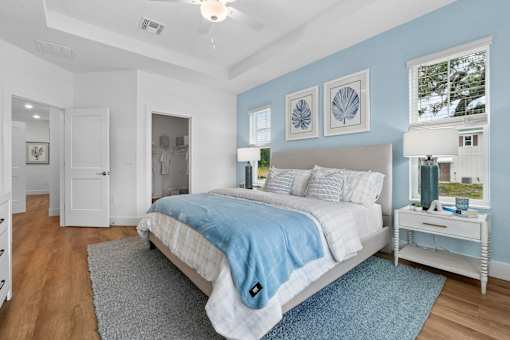 A bedroom with a bed, nightstand, and two framed pictures on the wall.