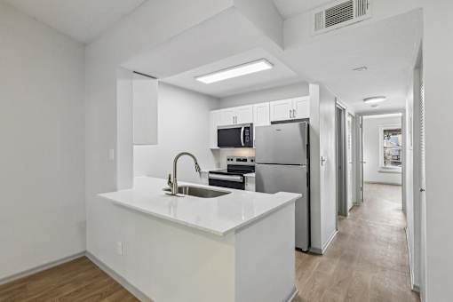 A modern kitchen with white countertops and stainless steel appliances.