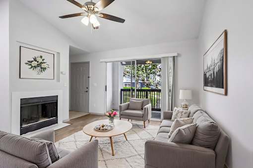 A living room with a grey couch, a coffee table, a fireplace, and a painting on the wall.