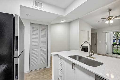 A kitchen with a black refrigerator, white cabinets, and a sink.