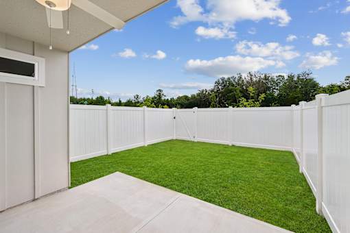 A white fenced backyard with a green lawn.