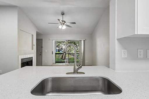 A modern kitchen with a stainless steel sink and a ceiling fan.
