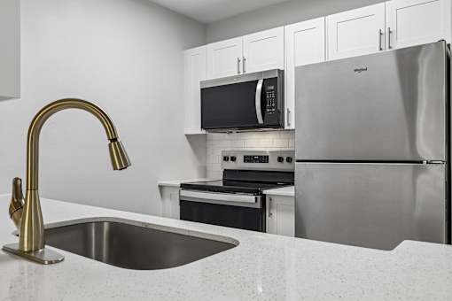 A kitchen with a sink, refrigerator, and microwave.